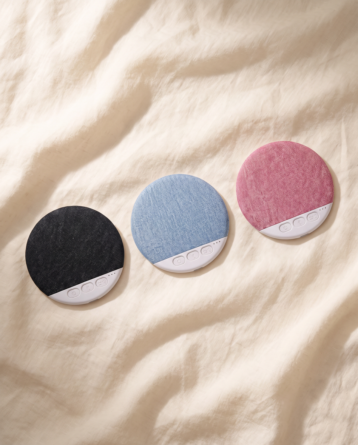 Undertone speakers in black, blue, and blush on cream linen